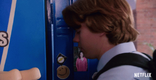 A Boy Standing In Front Of A Blue Locker With A Picture Of A Woman On It GIF