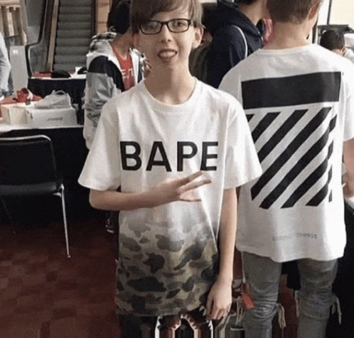 A Boy Wearing A Bape T-Shirt Stands In A Crowd Of People GIF