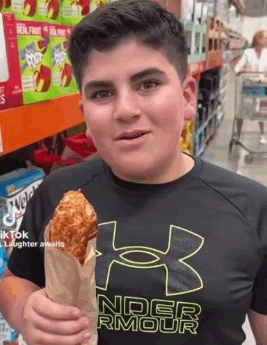 A Boy Wearing A Black Under Armour Shirt Is Holding A Fried Chicken In A Paper Bag GIF