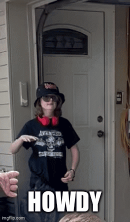 A Boy Wearing A Hat And Headphones Is Standing In Front Of A Door With The Word Howdy Written On It GIF
