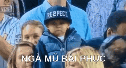 A Boy Wearing A Hat That Says Respect Is Sitting In A Crowd Of People . GIF