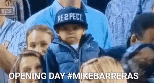 A Boy Wearing A Hat That Says Respect Is Sitting In A Crowd Of People . GIF