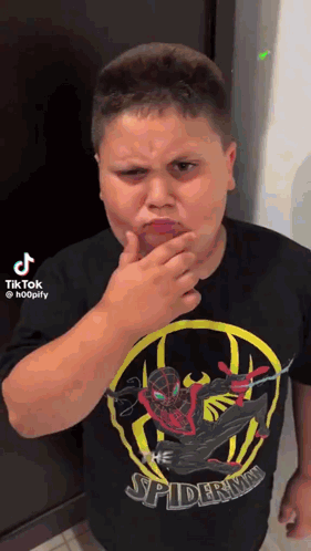 A Boy Wearing A Spiderman Shirt Is Making A Funny Face . GIF