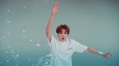 A Boy Wearing A White Shirt That Says Balenciaga Is Jumping In The Air GIF