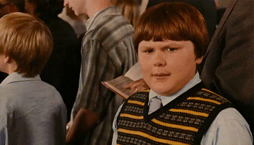 A Boy Wearing A Yellow And Black Striped Vest Looks At The Camera GIF