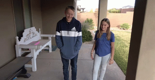 A Boy Wearing An Adidas Sweatshirt Stands Next To A Girl On A Porch GIF