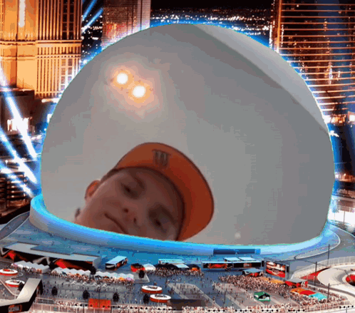 A Boy Wearing An Orange M & M 'S Hat Is Looking Out Of A Giant Dome GIF