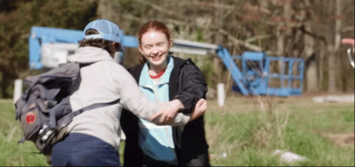 A Boy With A Backpack Is Hugging A Girl In A Field . GIF