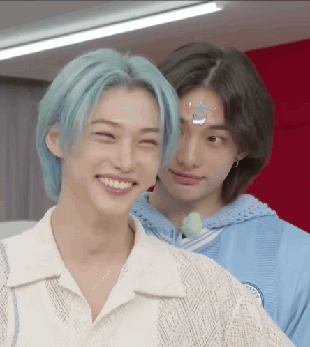 A Boy With Blue Hair Is Smiling Next To Another Boy With Black Hair . GIF