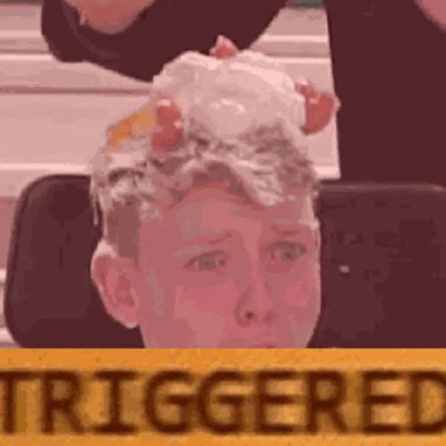 A Boy With Eggs On His Head Is Sitting In Front Of A Yellow Sign That Says Triggered . GIF
