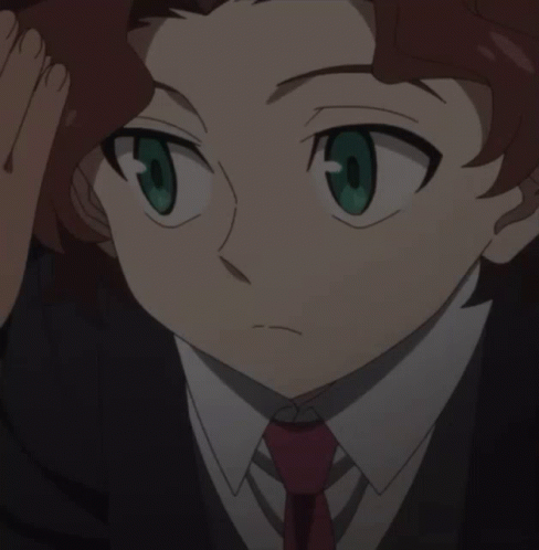 A Boy With Red Hair And Green Eyes Is Wearing A Black Suit And Red Tie GIF