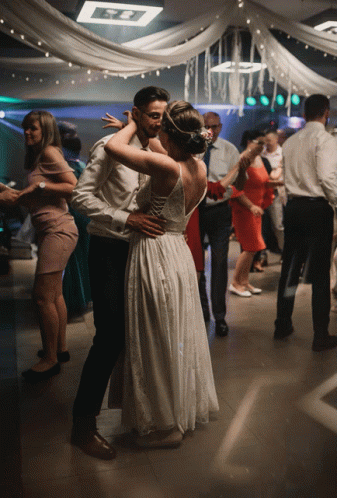 A Bride And Groom Are Dancing On A Dance Floor At A Wedding Reception GIF