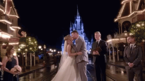 A Bride And Groom Are Kissing In Front Of A Castle GIF