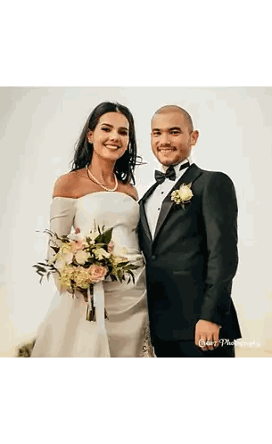 a bride and groom are posing for a picture and the bride is holding a bouquet