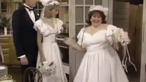 A Bride And Groom Are Standing In A Kitchen . GIF