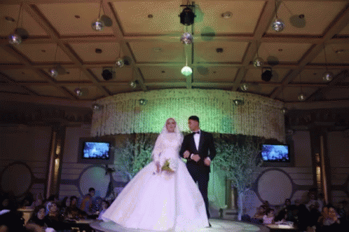 A Bride And Groom Are Walking Down The Aisle At A Wedding Reception GIF