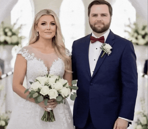 A Bride And Groom Pose For A Picture While The Bride Is Holding A Bouquet Of White Flowers GIF