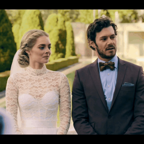 A Bride And Groom Standing Next To Each Other GIF