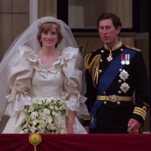 A Bride And Groom Standing Next To Each Other On Their Balcony GIF
