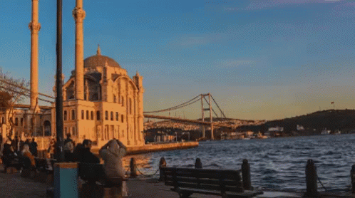 A Bridge Over A Body Of Water In Front Of A Mosque GIF