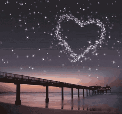 A Bridge Over A Body Of Water With A Heart Made Of Stars Above It GIF
