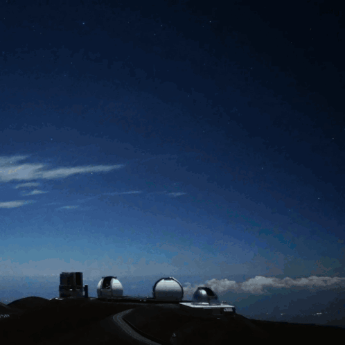 A Bright Light Shines Brightly In The Night Sky Above A Building GIF