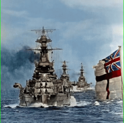 A British Flag Flies In Front Of A Row Of Ships GIF