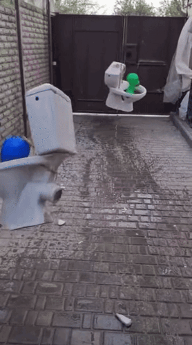 A Broken Toilet Sits On A Brick Sidewalk GIF