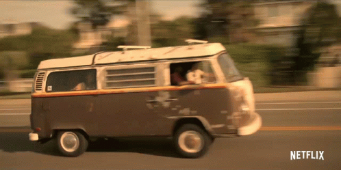 a brown and white van is driving down a street with netflix written on the bottom of the screen