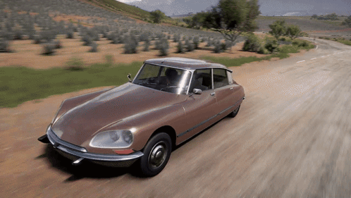 A Brown Car Is Driving Down A Dirt Road With Trees In The Background GIF