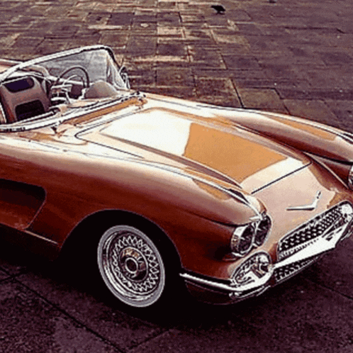 A Brown Sports Car With A Convertible Top Is Parked On The Side Of The Road GIF