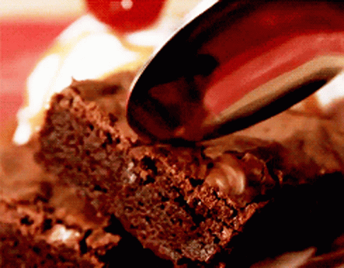 A Brownie Is Being Eaten With A Spoon And A Cherry In The Background GIF