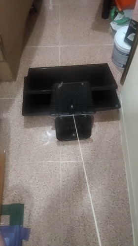 A Bucket Of Paint Sits On The Floor Next To A Shelf GIF