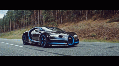 a bugatti chiron is driving down a road in the woods