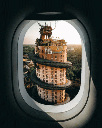 A Building With A Dragon On Top Of It Is Seen Through An Airplane Window GIF
