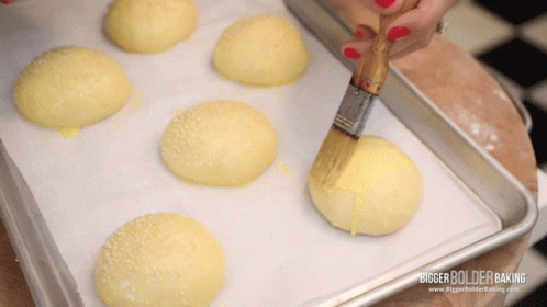 A Bunch Of Buns Are Sitting On A Tray With A Bigger Bolder Baking Logo On The Bottom GIF