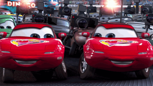 A Bunch Of Cars Are Lined Up In Front Of A Sign That Says Dinoco GIF