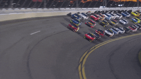 a bunch of cars are racing on a track with a sign that says ' toyota '