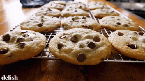 A Bunch Of Chocolate Chip Cookies On A Cooling Rack With The Word Delish Below Them GIF