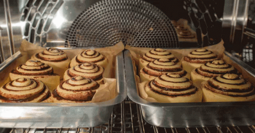 A Bunch Of Cinnamon Rolls Are In A Pan In An Oven GIF
