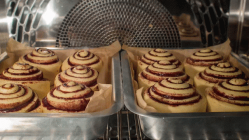 A Bunch Of Cinnamon Rolls Are In A Pan In An Oven GIF