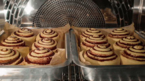 A Bunch Of Cinnamon Rolls Are In A Pan In An Oven GIF