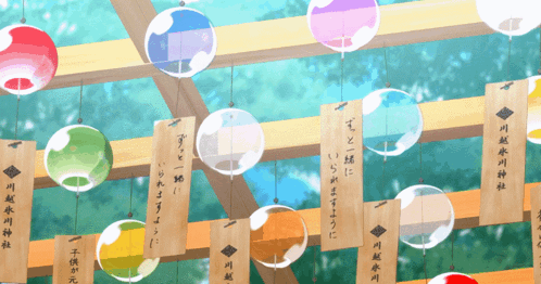 A Bunch Of Colorful Balls Hanging From A Wooden Beam With Chinese Writing On Them GIF