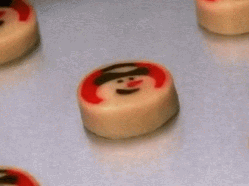 A Bunch Of Cookies With Snowmen On Them On A Table . GIF