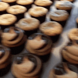 A Bunch Of Cupcakes With Frosting On Them Are Lined Up On A Table GIF