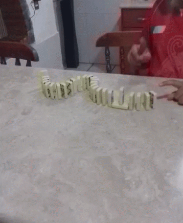 A Bunch Of Dominoes On A Table With A Person In A Red Dress In The Background GIF