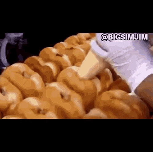 A Bunch Of Donuts Are Being Made In A Donut Shop . GIF