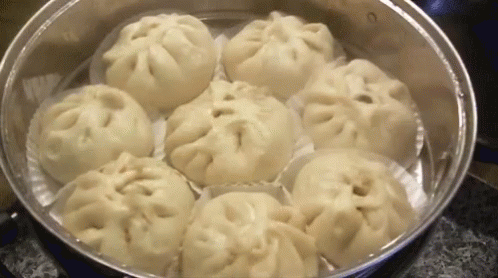 A Bunch Of Dumplings Are Cooking In A Steamer . GIF
