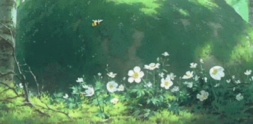 A Bunch Of Flowers Are Growing In The Grass Near A Rock GIF