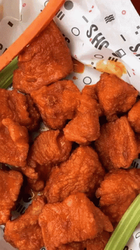 A Bunch Of Fried Chicken Wings With Celery And Carrots On A Paper That Says Shc GIF